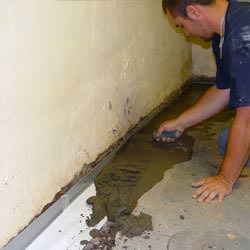A basement waterproofer installing a perimeter drain system in Shawano