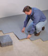 Contractors installing basement sub floor tiles and matting on a concrete basement floor in Wausau, Wisconsin