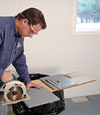 installing a waterproof vapor barrier on a basement floor to prepare for basement carpeting in a Sheboygan home