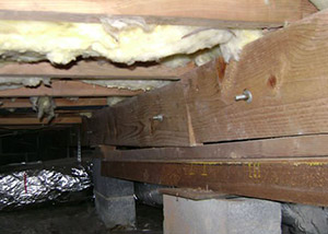 A sagging crawl space with concrete supports and wooden shimming a Manitowoc crawl space